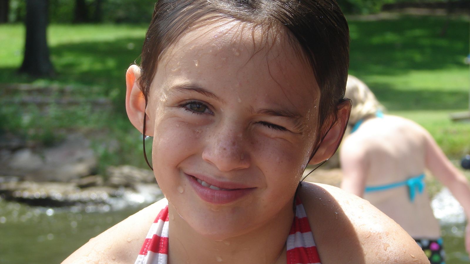 Gracey as a girl smiling by the creek