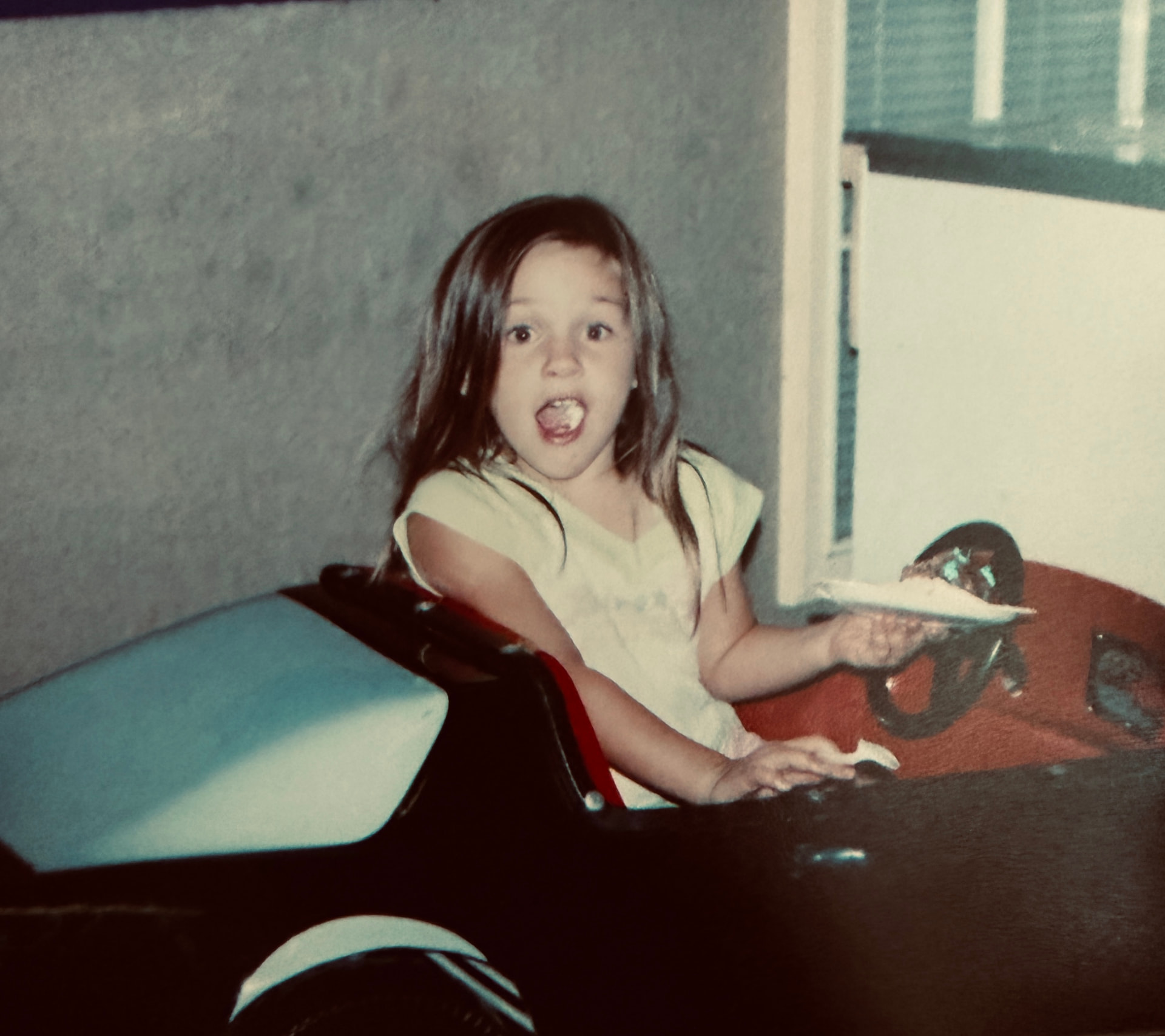Gracey as a little girl in a toy car