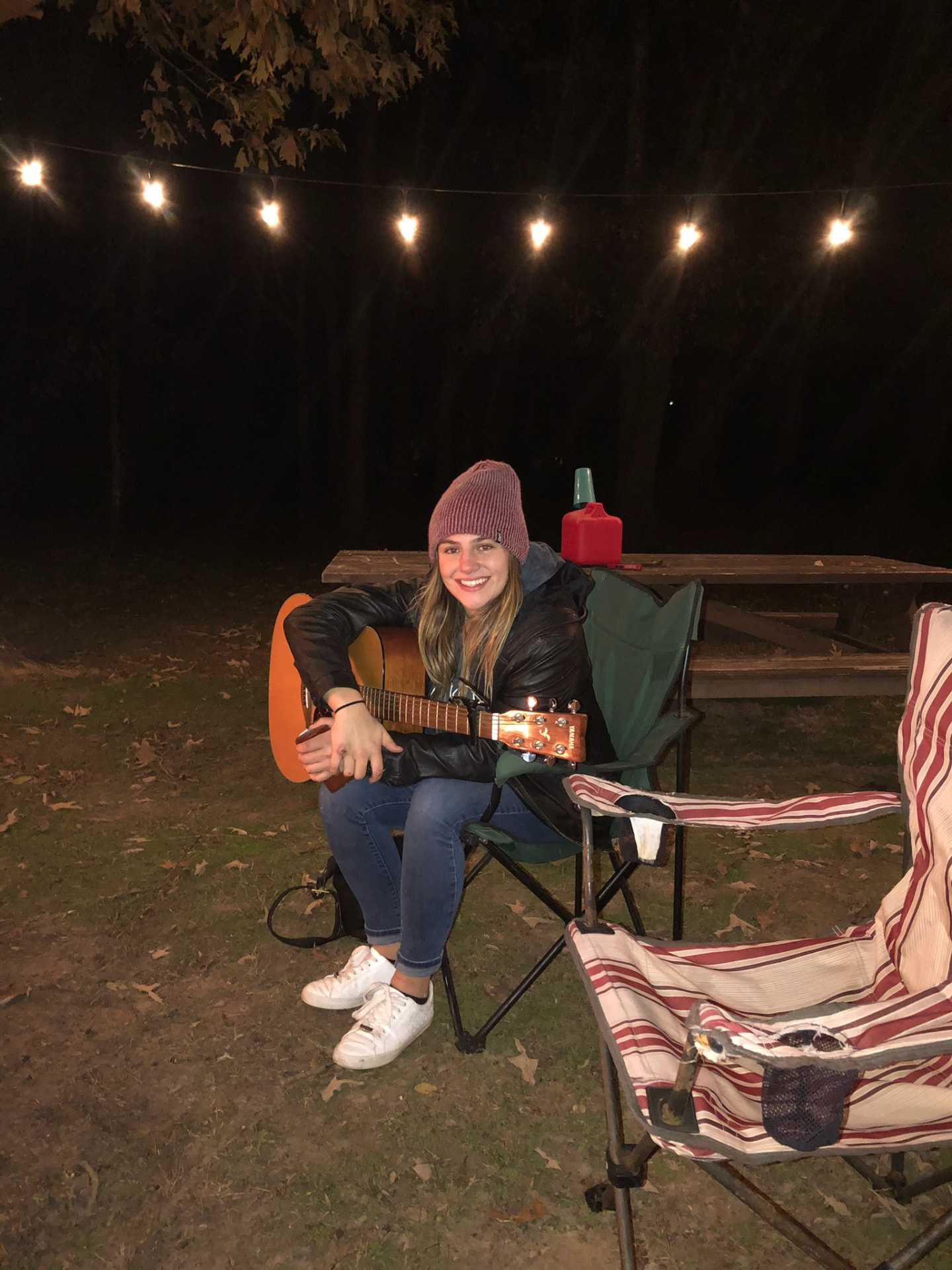 Gracey playing guitar under string lights at night