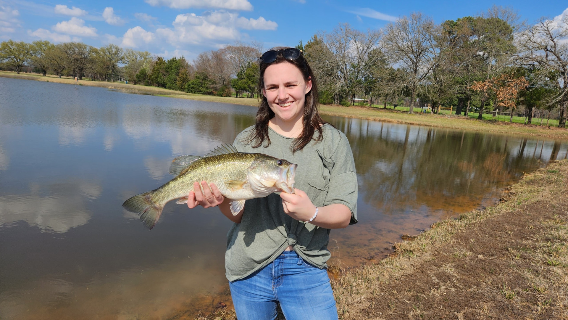 Gracey holding a bass beside a pond